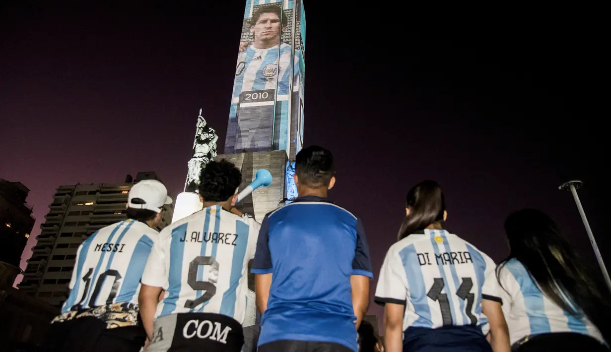 Video mapping memperlihatkan gambar bintang sepak bola Argentina Lionel Messi dan Angel Di Maria di "Monumento Nacional a la Bandera" di Rosario, Senin (21/11/2022). Proyeksi tersebut mengulas gambar Messi di berbagai Piala Dunia yang dimainkan dari tahun 2006 hingga sekarang. (Marcelo Manera / AFP)