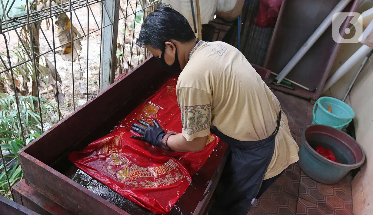 Perajin menyelesaikan salah satu tahapan produksi batik Marunda di Rusunawa Marunda, Jakarta, Selasa (14/7/2020). Pembuatan batik Marunda dimulai dengan melukis pola, mencelup, hingga memberikan warna. (Liputan6.com/Herman Zakharia)