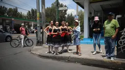 Balerina  atau penari balet menunggu di persimpangan jalan Mexico City untuk menampilkan tarian balet, 28 Juli 2018. Para balerina dari sanggar Ardentia itu melakukan pertunjukan 58 detik sesuai durasi lampu lalu lintas Kota Meksiko. (AP/Emilio Espejel)