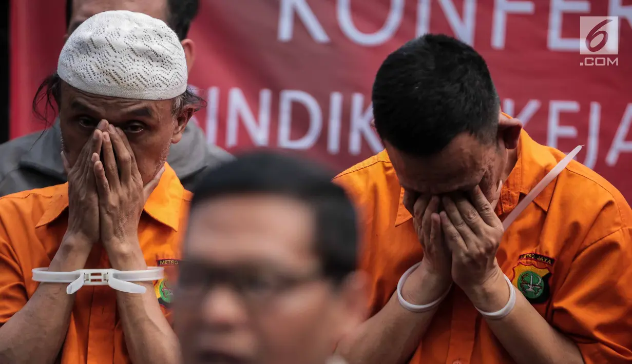 Dua tersangka menutupi wajahnya saat rilis pengungkapan sindikat kejahatan properti di kawasan Tebet Timur Raya, Jakarta, Senin (5/8/2019). Subdit 2 Harda Dit Reskrimum PMJ mengamankan 5 tersangka dengan barang bukti seperti sertifikat palsu korban dan satu buah laptop. (Liputan6.com/Faizal Fanani)
