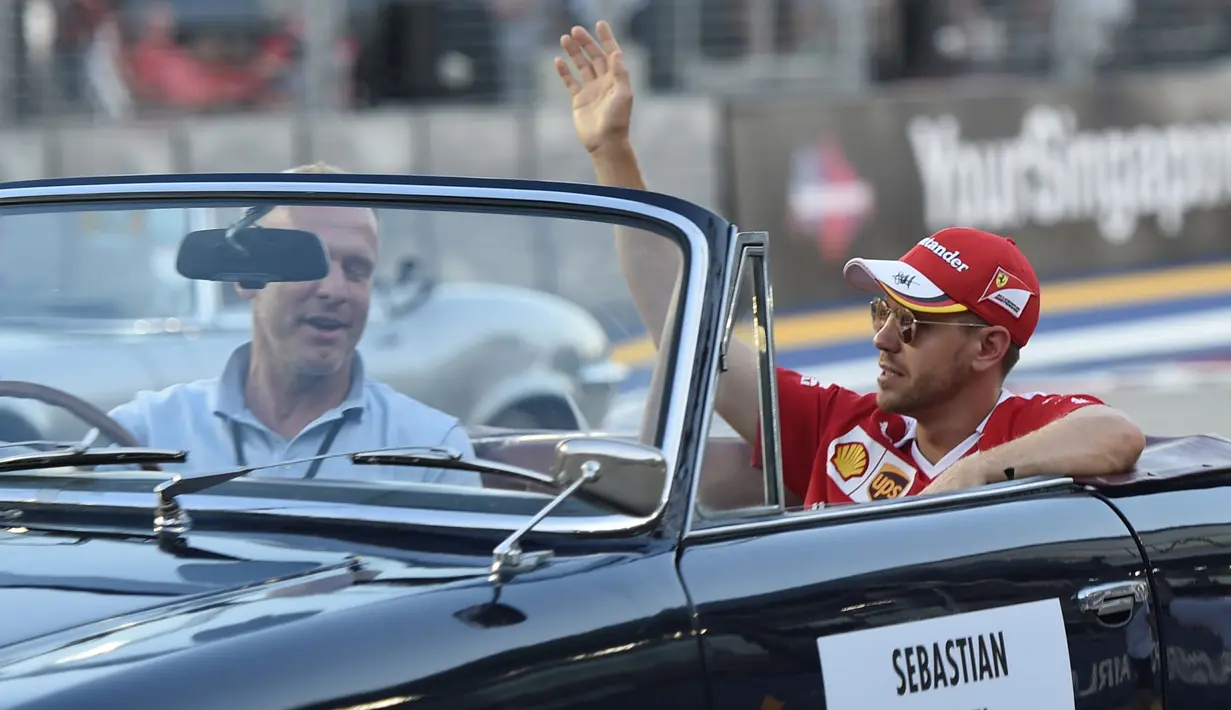 Pembalap Formula 1 Ferrari asal Jerman, Sebastian Vettel menyapa pengemar saat di mobil Mercedes-Benz klasik saat mengikuti parade jelang Grand Prix Formula 1 Malaysia di Sirkuit Internasional Sepang, Malaysia, (2/10). (AFP PHOTO/Anthony Wallace)