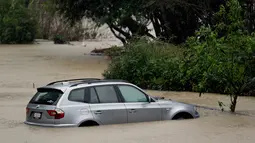 Sebuah mobil terendam di dekat Sungai Rusia yang meluap dan menyebabkan di Guerneville, California, AS, Selasa (10/1). Cuaca ektrem "Pineapple Express" yang membawa kelembapan dari Hawaii menciptakan hujan badai. (AP Photo / Eric Risberg)