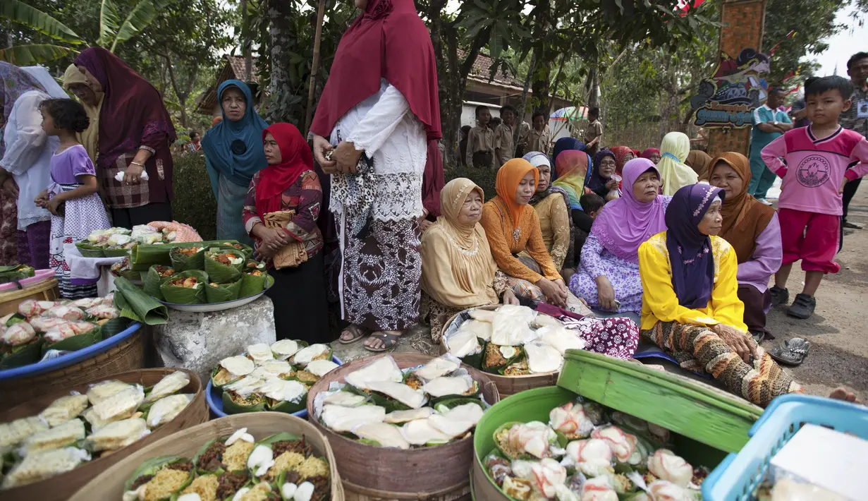 Warga berdiri di dekat makanan dan hasil pertanian jelang ritual sedekah bumi di Desa Karang Jati, Banjarnegara, Jateng, Jumat (23/10). Ini bentuk penghormatan terhadap Tuhan dan alam agar terhindar dari kemarau berkepanjangan. (REUTERS/Nicholas Owen)