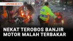 Ada sepeda motor terbakar setelah nekat menerobos banjir di Jalan Raya Daan Mogot, Cengkareng, Jakarta Barat. Untuk memadamkan api, seorang polisi mendorong sepeda motor dan menceburkannya ke jalan yang terendam banjir.