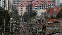 Warga beraktivitas di antara rel kereta dengan latar belakang gedung bertingkat di kawasan Pejompongan, Jakarta, Selasa (5/1/2021). Pemerintah mengalokasikan anggaran untuk PEN 2021 sebesar Rp403,9 triliun, anggaran ini naik dari rencana sebelumnya sebesar Rp372,3 triliun. (Liputan6.com/Johan Tallo)