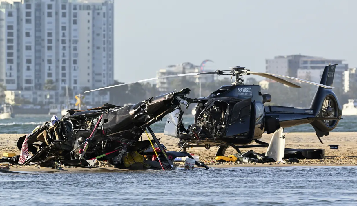 Dua helikopter yang hancur terlihat di pasir di lokasi tabrakan dekat Seaworld, di Gold Coast, Australia, Senin, 2 Januari 2023. Dua helikopter bertabrakan di udara menewaskan empat orang termasuk sepasang suami istri dari Inggris dalam kecelakaan yang menarik bantuan darurat dari pengunjung pantai selama musim panas. (Dave Hunt/AAP Image via AP)