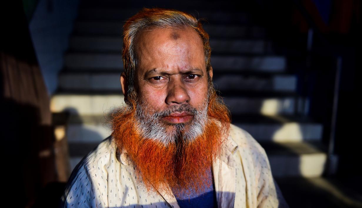 Dalam gambar yang diambil pada 24 Desember 2018, pedagang kaki lima bernama Amir Hossain dengan janggut oranye di Dhaka. Para pria tua yang ingin tetap merasa muda mewarnai janggut dengan henna, pewarna tradisional yang sudah terkenal di Bangladesh beberapa dekade lamanya. (MUNIR UZ ZAMAN / AFP)