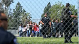Petugas kepolisian mengevakuasi para siswa setelah insiden penembakan di SD North Park di San Bernardino, California, Senin (10/4). Polisi menyebut aksi itu sebagai pembunuhan yang diikuti bunuh diri sang pelaku (Rick Sforza/Los Angeles Daily News via AP)