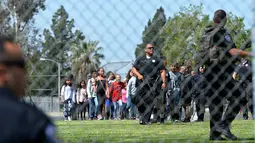 Petugas kepolisian mengevakuasi para siswa setelah insiden penembakan di SD North Park di San Bernardino, California, Senin (10/4). Polisi menyebut aksi itu sebagai pembunuhan yang diikuti bunuh diri sang pelaku (Rick Sforza/Los Angeles Daily News via AP)