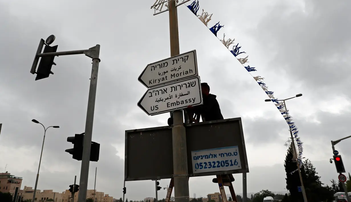 Pekerja memasang papan penunjuk jalan menuju Kedutaan Besar Amerika Serikat (AS) di Yerusalem, Senin (7/5). Rambu jalan yang ditulis dalam bahasa Inggris, Ibrani dan Arab itu dipasang dekat lokasi kedutaan di Yerusalem selatan. (AFP/THOMAS COEX)