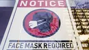 Sebuah tanda yang mewajibkan masker dipasang di depan toko di Philadelphia, Rabu (16/2/2022). Pejabat kota Philadelphia mencabut mandat vaksin untuk makan di dalam ruangan dan tempat lain yang menyajikan makanan dan minuman, tetapi mandat masker dalam ruangan tetap berlaku. (AP Photo/Matt Rourke)