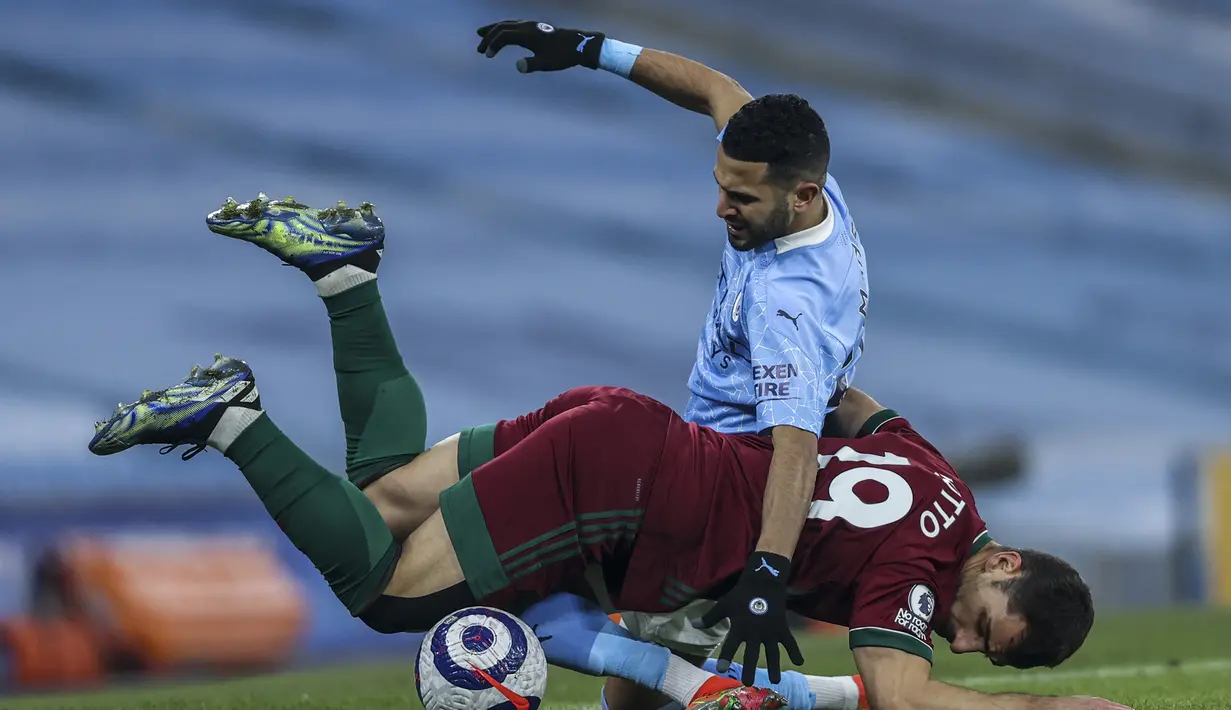 Bek Wolverhampton Wanderers, Jonny Otto (bawah) dan gelandang Manchester City, Riyad Mahrez terjatuh usai perebutan bola dalam laga lanjutan Liga Inggris 2020/21 pekan ke-27 di Etihad Stadium, Selasa (2/3/2021). Wolverhampton kalah 1-4 dari Manchester City. (AP/Clive Brunskill/Pool)