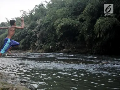 Seorang anak melompat ke Sungai Ciliwung, Depok, Jawa Barat, Kamis (4/7/2019). Menurunnya debit air Sungai Ciliwung akibat musim kemarau dimanfaatkan warga setempat sebagai tempat wisata gratis untuk mengajak anak berenang. (merdeka.com/Iqbal Nugroho)