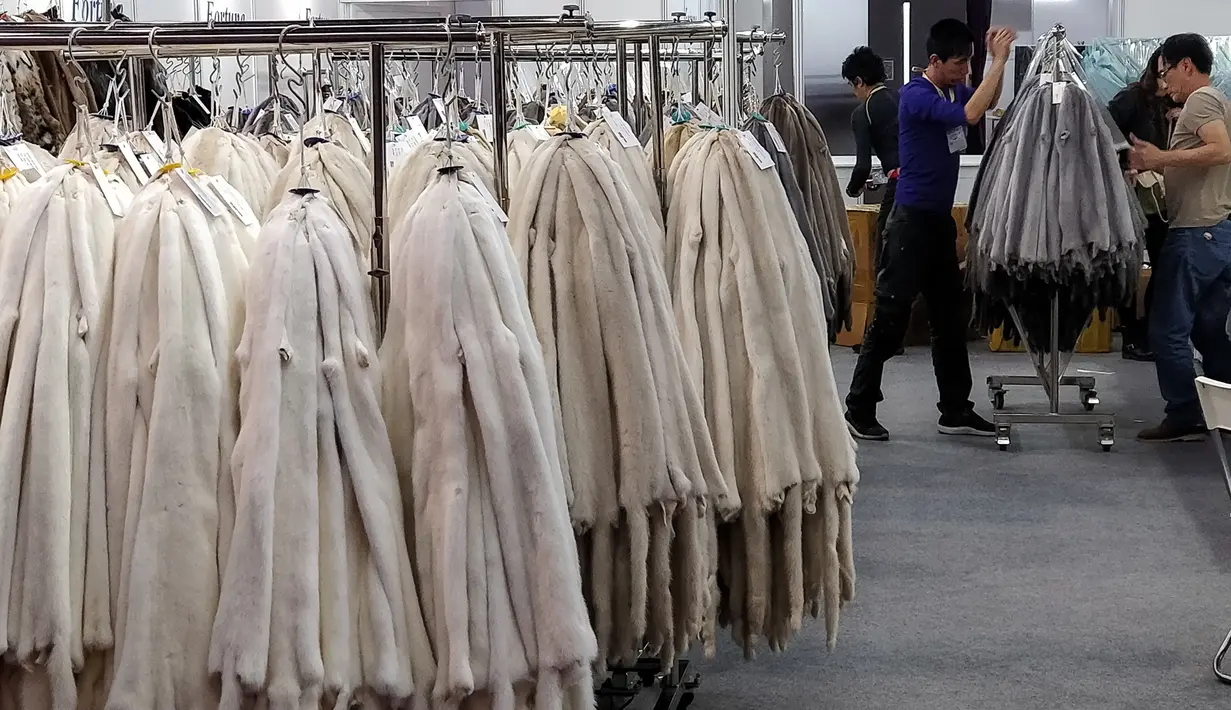 Para pekerja merapikan pakaian yang terbuat dari bulu binatang di Hong Kong International Fur and Fashion Fair di Hong Kong, Sabtu (24/2). (VIVEK PRAKASH/AFP)