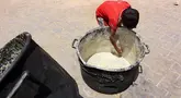 Seorang anak laki-laki Palestina mengorek sisa-sisa sup kacang miju-miju yang tersisa di dalam panci, di depan titik distribusi makanan di kamp pengungsian dekat pelabuhan Kota Gaza pada 22 Mei 2025. (Omar AL-QATTAA/AFP)
