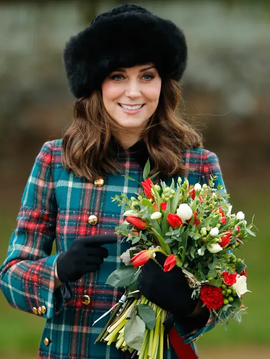 Kate Middleton menggenggam buket bunga usai tradisi kebaktian Hari Natal Kerajaan Inggris di Gereja St. Mary Magdalene, Sandringham, Senin (25/12). Kate membiarkan rambut coklatnya tergerai dan riasan wajah natural dengan lipstik nude. (AP/Alastair Grant)