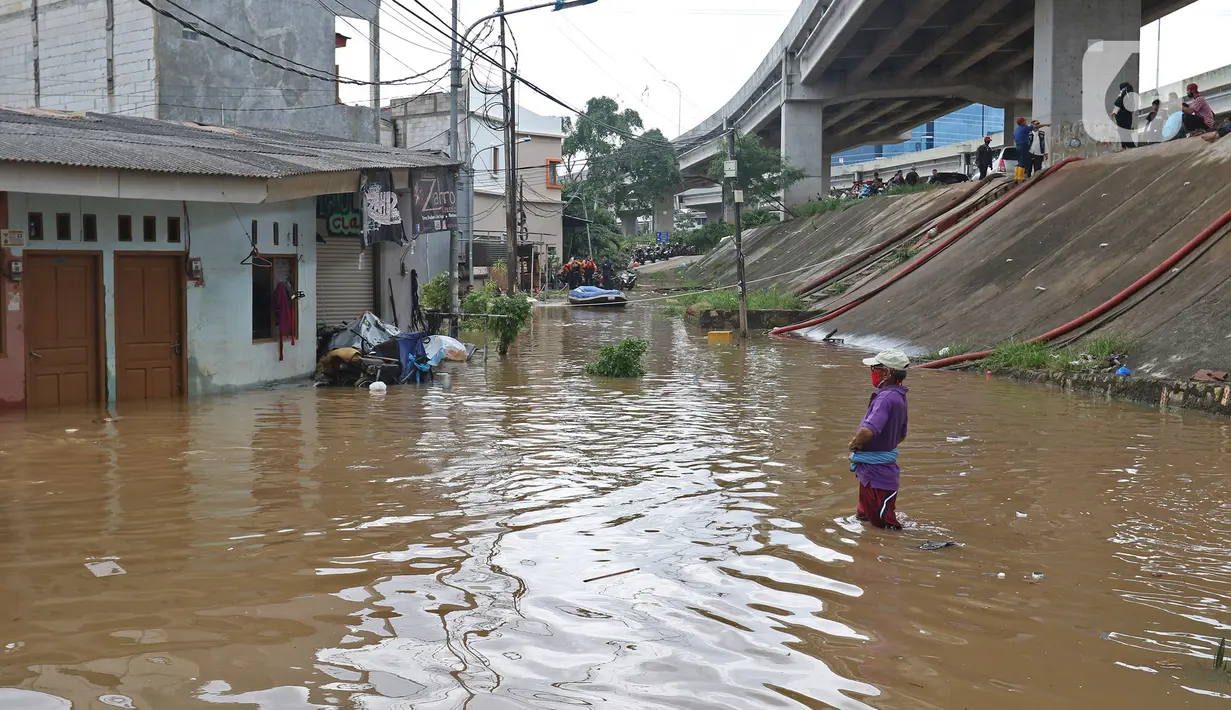 Seorang pria berdiri di tengah banjir yang merendam kawasan Cipinang Melayu, Jakarta Timur, Jumat (19/2/2021). Banjir di kawasan tersebut akibat curah hujan yang tinggi dan meluapnya air dari Kali Sunter. (Liputan6.com/Herman Zakharia)
