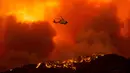 Helikopter bersiap untuk menjatuhkan air ke api yang membakar Hutan Nasional Angeles di California, Amerika Serikat, Rabu (12/8/2020). Kebakaran yang diberi nama Lake Fire tersebut terjadi di sekitar Danau Hughes. (AP Photo Ringo H.W. Chiu)