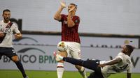 Striker AC Milan, Zlatan Ibrahimovic, dihadang oleh pemain Bologna, Stefano Denswil, pada laga Serie A di Stadion San Siro, Sabtu (18/7/2020). AC Milan menang dengan 5-1 atas Bologna. (AP/Luca Bruno)