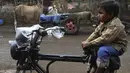 Seorang anak duduk di atas becak seekor sapi ditutupi dengan karung goni di pinggir jalan di New Delhi, India, Selasa (5/1/2021). Pemilik sengaja memakaikan penutup pada tubuh sapi untuk melindungi sapi dari cuaca dingin. (Photo by Sajjad HUSSAIN / AFP)