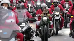 Pengendara sepeda motor yang mengenakan kostum Sinterklas mengendarai motor mereka selama parade Sinterklas di Beograd, Serbia, Minggu (26/12/2021). Mereka melakukan konvoi menuju rumah sakit anak-anak untuk membagikan mainan hadiah Natal kepada pasien di sana. (AP Photo/Darko Vojinovic)