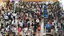 Puluhan calon penumpang berkerumun di lobi keberangkatan Bandara Haneda di Tokyo, Senin (22/8). Topan Mindulle yang bergerak menuju Tokyo menyebabkan hampir 400 penerbangan dibatalkan akibat hujan lebat dan angin kencang. (Jiji Press/AFP)