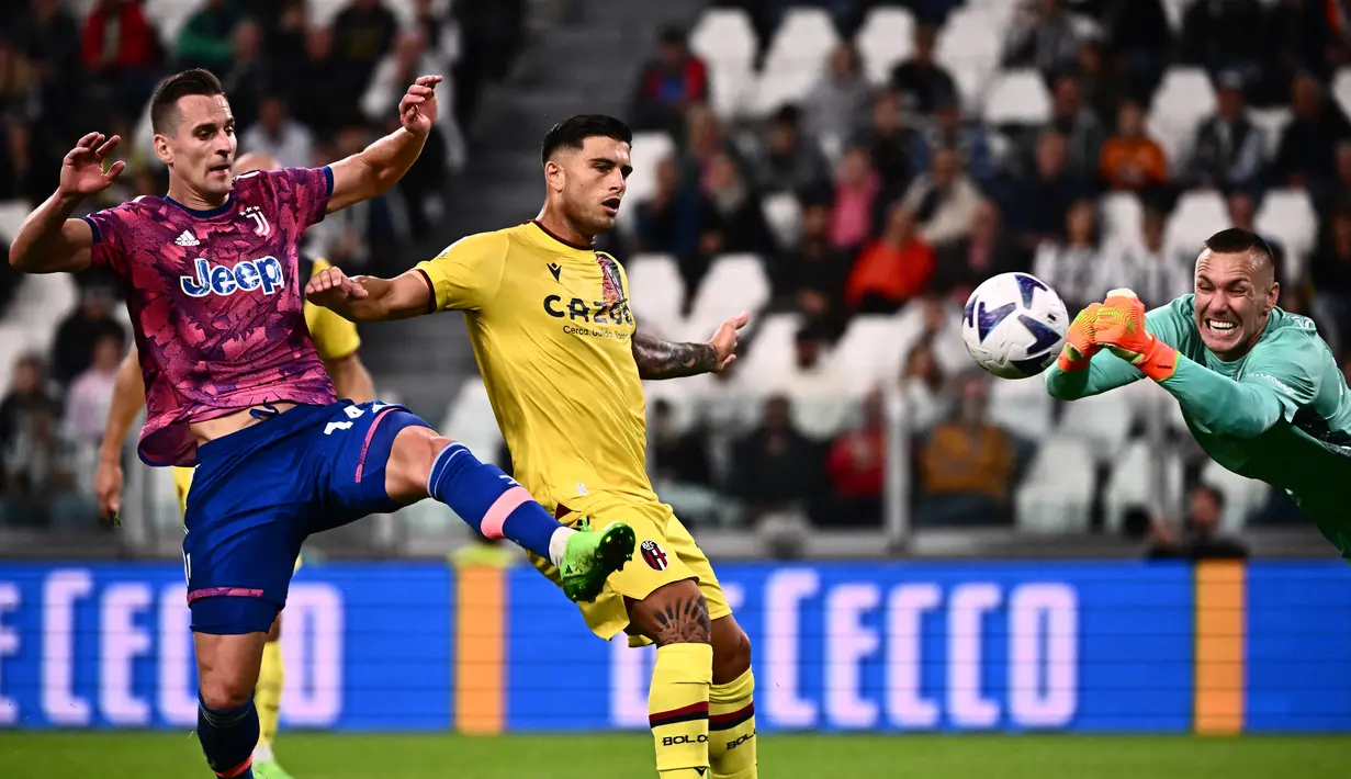 Pemain depan Juventus Arkadiusz Milik (kiri) menantang kiper Bologna Lukasz Skorupski (kanan) pada pekan kedelapan Liga Italia 2022-2023 di Allianz Stadium, Senin (3/10/2022) dini hari WIB. Juventus berhasl melibas Bologna dengan skor meyaknkan 3-0. (Photo by Marco BERTORELLO / AFP)