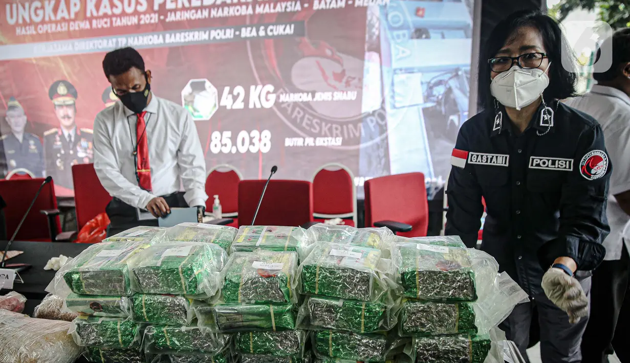 Petugas menata barang bukti terkait upaya penyelundupan narkoba jaringan Malaysia saat rilis di Gedung Bareskrim Mabes Polri, Jakarta, Selasa (30/3/2021). Total barang bukti yang disita ada 42 kilogram lebih narkotika jenis sabu dan 83 ribu butir pil ekstasi. (Liputan6.com/Faizal Fanani)