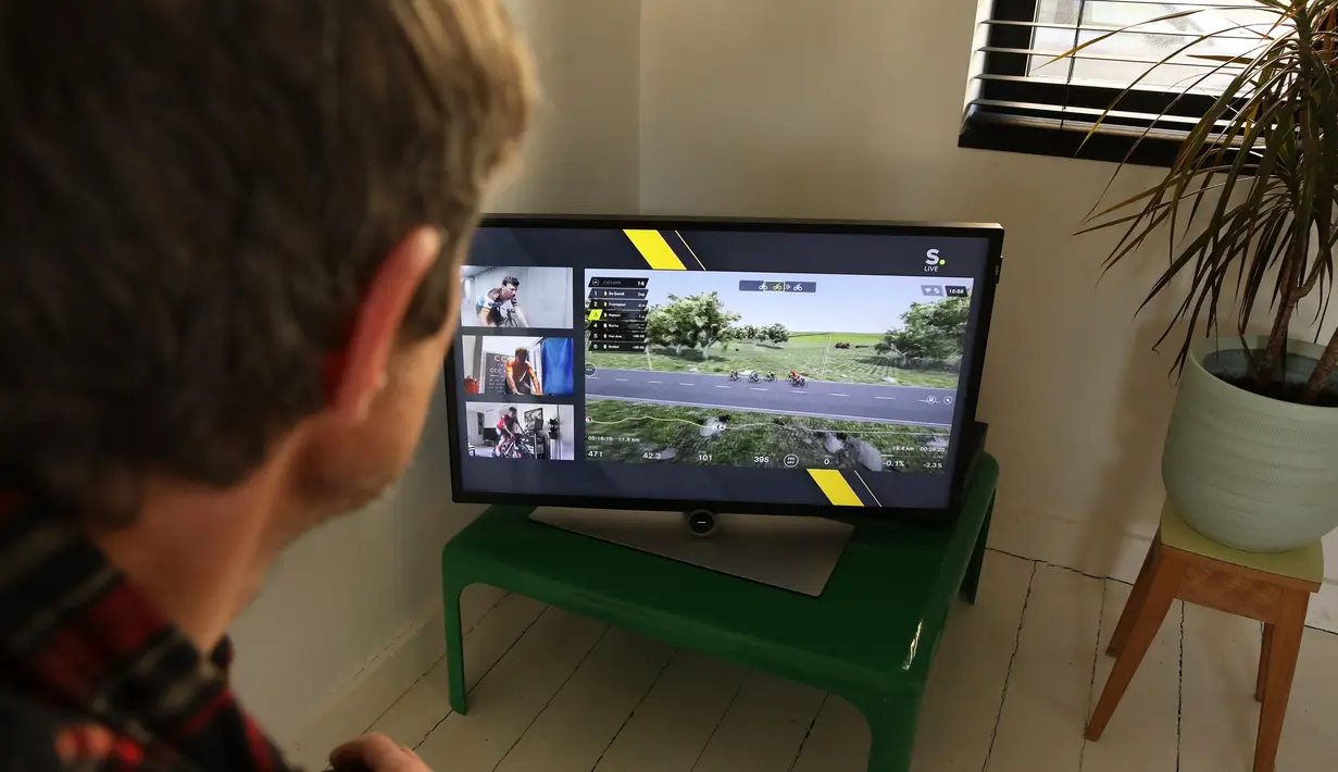 Seorang pria menyaksikan Tour of Flanders yang diselenggarakan secara virtual di sebuah televisi, di Vilvoorde (5/4/2020). Balap sepeda virtual ini digelar untuk menggantikan Tour of Flanders 2020 yang ditunda penyelenggaraannya lantaran meluasnya penyebaran Covid-19. (AFP/Belga/Nathalie Willems)