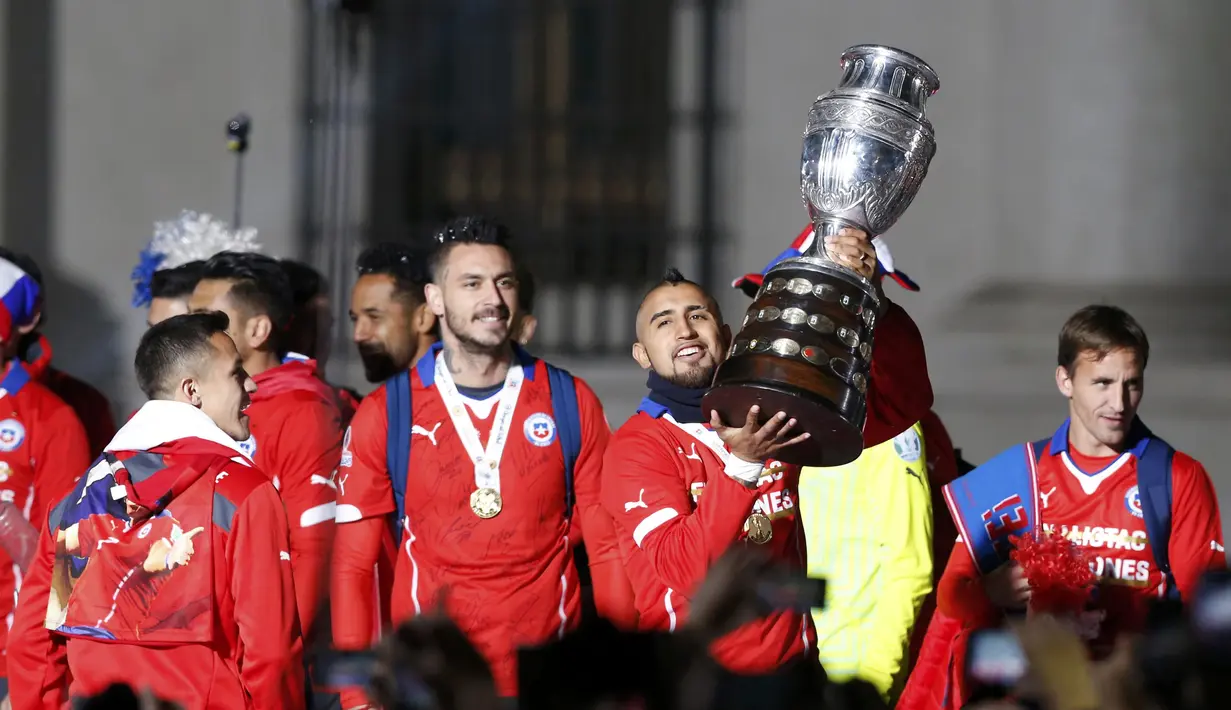 Arturo Vidal dan rekan-rekannya dengan trofi Copa America menyambut suporter Cile dari balkon Istana Presiden. (REUTERS/Carlos Garcia Rawlins)