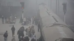 Para penumpang menaiki kereta di tengah kabut tebal di sebuah stasiun kereta api di Kota Lahore, Pakistan timur, pada 13 Desember 2020. Kabut tebal menyelimuti sejumlah kota di Pakistan, sehingga meminimalkan jarak pandang dan mengganggu lalu lintas jalan. (Xinhua/Sajjad)