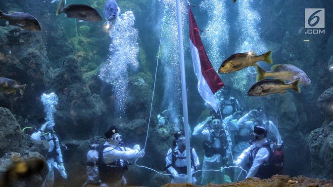 Penyelam mengibarkan bendera Merah Putih di Seaworld Ancol, Jakarta, Jumat (17/8). Artis peran Marsha Aruan terpilih sebagai salah satu pengibar bendera di dalam air memperingati HUT ke-73 Republik Indonesia. (Liputan6.com/Faizal Fanani)
