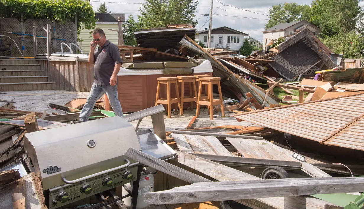 Seorang pria melewati puing-puing rumahnya akibat tornado di Lachute, Barat laut Montreal, Quebec, Rabu (23/8). Badai tornado EF-1 mencapai sekitar 175 km/jam melanda kota-kota di Kanada. (Ryan Remiorz/The Canadian Press via AP)