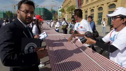 Juri Guinness, Swapnil Dangarikar menyaksikan pengukuran syal tenun tangan yang dikenal sebagai Krama pada upaya pemecahan rekor di Phnom Penh, Kamboja, Minggu (1/7). Syal krama di Kamboja masuk dalam buku Guinness World Records. (AFP/TANG CHHIN Sothy)