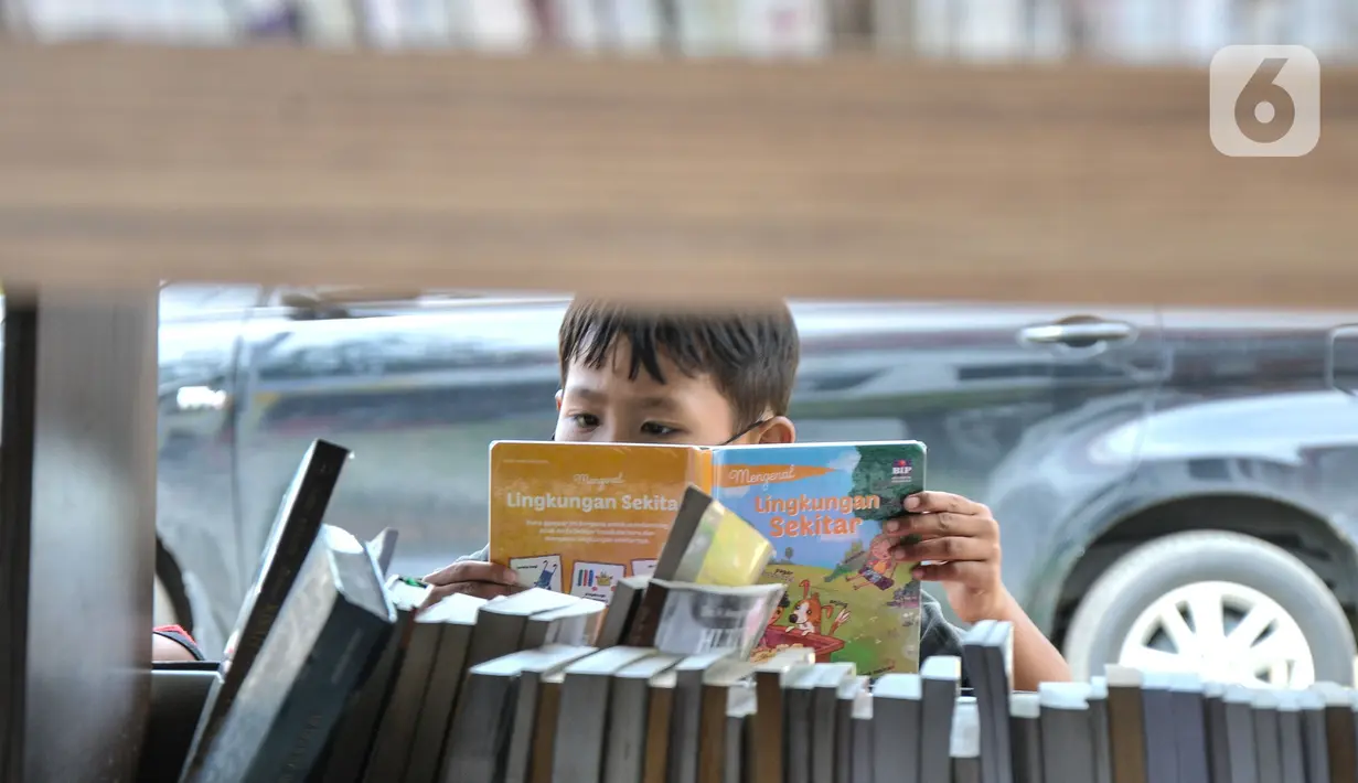 Seorang anak membaca buku di Perpustakaan Keliling kawasan Jatinegara, Jakarta, Rabu (29/9/2021). Mobil Perpustakaan Keliling yang difasilitasi Dinas Perpustakaan dan Kearsipan DKI itu merupakan sarana dan upaya pemerintah dalam meningkatkan minat baca anak sejak dini. (merdeka.com/Iqbal S Nugroho)
