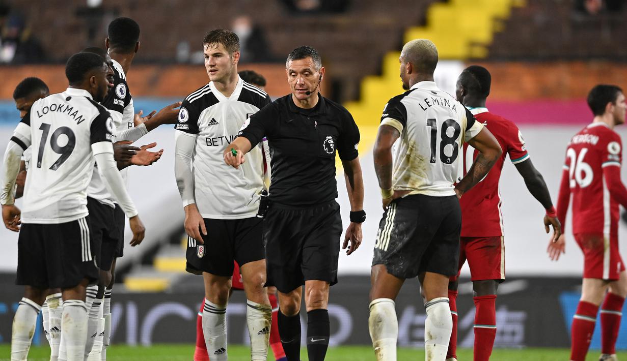 Para pemain Fulham memprotes keputusan wasit Andre Marriner yang memberi tendangan penalti untuk Liverpool dalam laga lanjutan Liga Inggris 2020/21 pekan ke-12 di Craven Cottage, Minggu (13/12/2020). Fulham bermain imbang 1-1 dengan Liverpool. (AFP/Mike Hewitt/Pool)