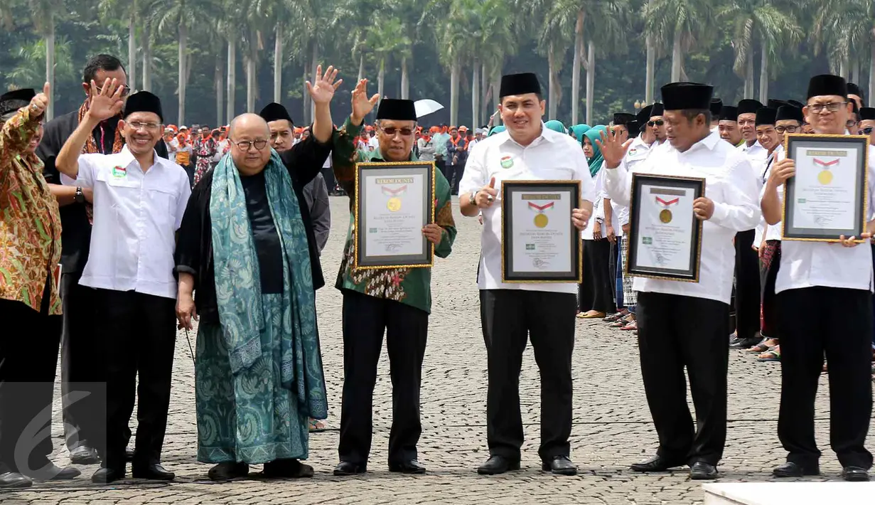 Ketua MURI Jaya Suprana memberikan piagam untuk pembacaan serentak 1 miliar shalawat Nariyah dan kirab terjauh kepada Ketum PBNU Said Aqil Siradj dan pengurus PBNU dalam Hari Santri Nasional di Monas, Jakarta, Sabtu (22/10). (Liputan6.com/Fery Pradolo)