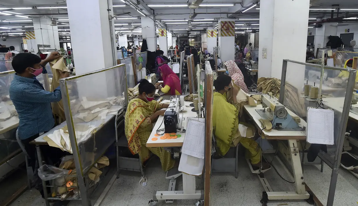 Para buruh bekerja pada stasiun mereka yang dipisahkan oleh sekat sebagai tindakan pencegahan terhadap penularan virus corona COVID-19 di pabrik garmen Civil Engineers Limited, Dhaka, Bangladesh, 17 Agustus 2021. (Munir UZZAMAN/AFP)