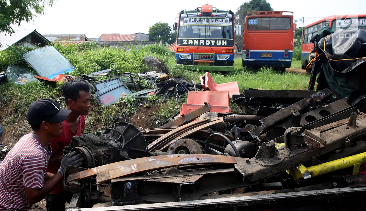 Pekerja mengangkut dan memindahkan bagian mesin dari angkutan Metromini di salah satu pool Metromini, Jalan Pulogebang, Jakarta, Rabu (3/1). (Liputan6.com/JohanTallo)