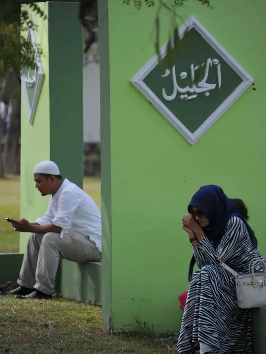 Warga Aceh berdoa di pemakaman massal Ulhee Lheue, Banda Aceh, Sabtu (26/12/2015).  Doa tersebut untuk keluarga mereka yang terkena bencana Tsunami pada 26 Desember 2014. (AFP Photo/ Chaideer Mahyuddin)