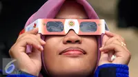 Seorang mahasiswi mencoba kacamata yang akan di gunakan untuk mengamati gerhana matahari di taman Pintar Yogyakarta, (2/3). Kawasan Tugu menjadi salah satu tempat pengamatan gerhana matahari pada 9 Maret 2016. (Liputan6.com/Boy Harjanto)