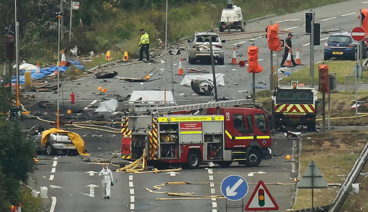 Tim penyelamat dan petugas investigasi berada di lokasi jatuhnya jet Hawker Hunter di Jalan Raya A27, Shoreham, Inggris, Minggu (23/8/2015). Pesawat yang tengah mengikuti Shoreham Airshow tersebut menewaskan sedikitnya tujuh orang.(REUTERS/Luke MacGregor)