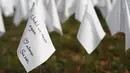 Sebuah bendera putih dengan pesan ditanam untuk mengenang warga Amerika yang meninggal karena COVID-19 di dekat Stadion RFK di Washington, Selasa (27/10/2020). Instalasi seni Suzanne Brennan Firstenberg itu disebut "In America, How Could This Happen.” (AP/Patrick Semansky)