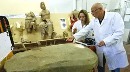 Stefano Sarri dan asistennya saat melakukan restorasi terhadap prasasti Etruscan di Florence , Italia , 20 April 2016.Prasasti itu ditemukan tertanam dalam pondasi kuil yang terkubur selama lebih dari 2.500 tahun. (REUTERS / Remo Casilli)