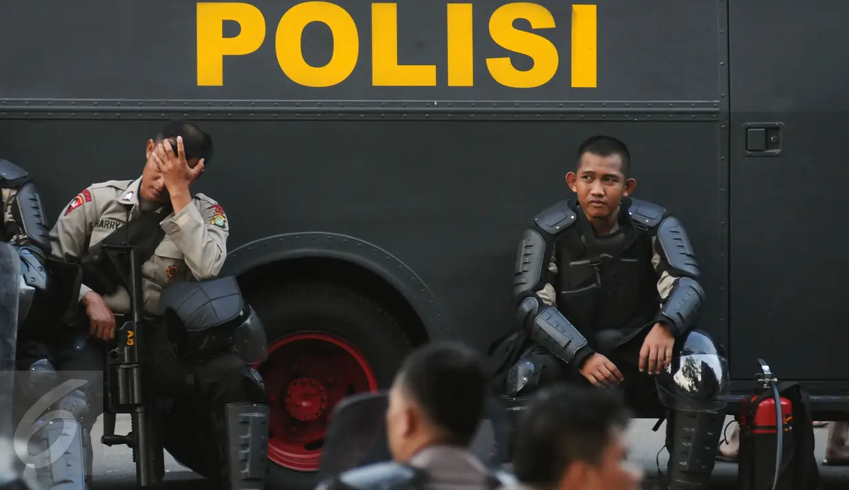 Polisi beristirahat di samping kendaraan taktis di depan Istana Negara, Jakarta, Jumat (4/11). Ribuan aparat gabungan disiagakan saat massa melakukan aksi menuntut penegakan hukum kasus dugaan penistaan agama. (Liputan6.com/Helmi Fithriansyah)