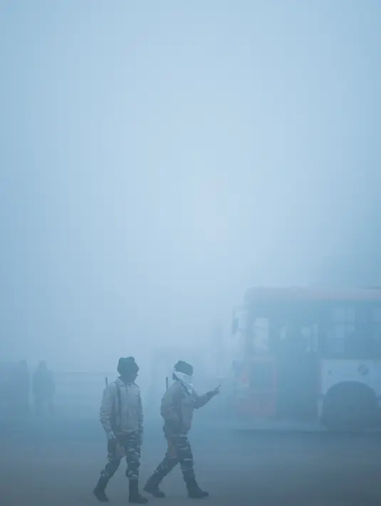 Tentara berpatroli di sepanjang jalan dalam kondisi berkabut akibat suhu dingin di New Delhi, Senin (30/12/2019). New Delhi, ibu kota India, saat ini mengalami musim dingin dengan hari dingin terpanjang dalam 22 tahun terakhir. (Photo by Jewel SAMAD / AFP)