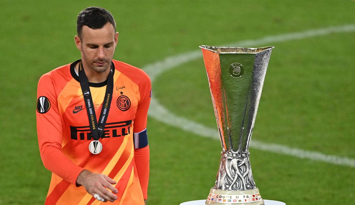 Kiper Inter Milan, Samir Handanovic berjalan melewati trofi setelah kalah dari Sevilla pada laga final Liga Europa 2019/2020 di RheinEnergieStadion, Jerman, 21 Agustus 2020. (AFP/Pool/Ina Fassbender)