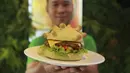 Pemilik restoran Hoang Tung menunjukkan burger berbentuk virus corona COVID-19 di Hanoi, Vietnam, Rabu (25/3/2020). Sebuah restoran di Hanoi membuat kreasi baru mereka yang disebut ‘Burger Corona’. (AP Photo/Hau Dinh)