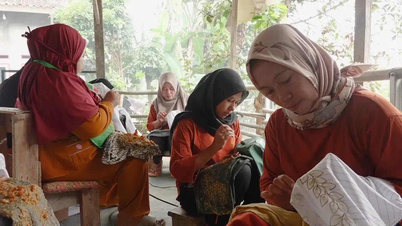Perajin batik pewarna alami berbahan limbah kulit jengkol saat menggoreskan canting membuat motif khas budaya Lampung. (Liputan6.com/Ardi Munthe)