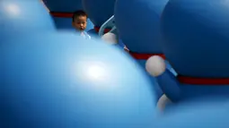 Seorang anak kecil saat bermain di antara patung – patung Doraemon, Seoul, Korea Selatan,Senin (31/8/2015). Pameran ini berlangsung dari 28 Agustus sampai 4 oktober. (REUTERS/Kim Hong – Ji)